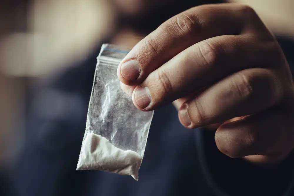 man hand holds plastic packet or bag with cocaine or another drug