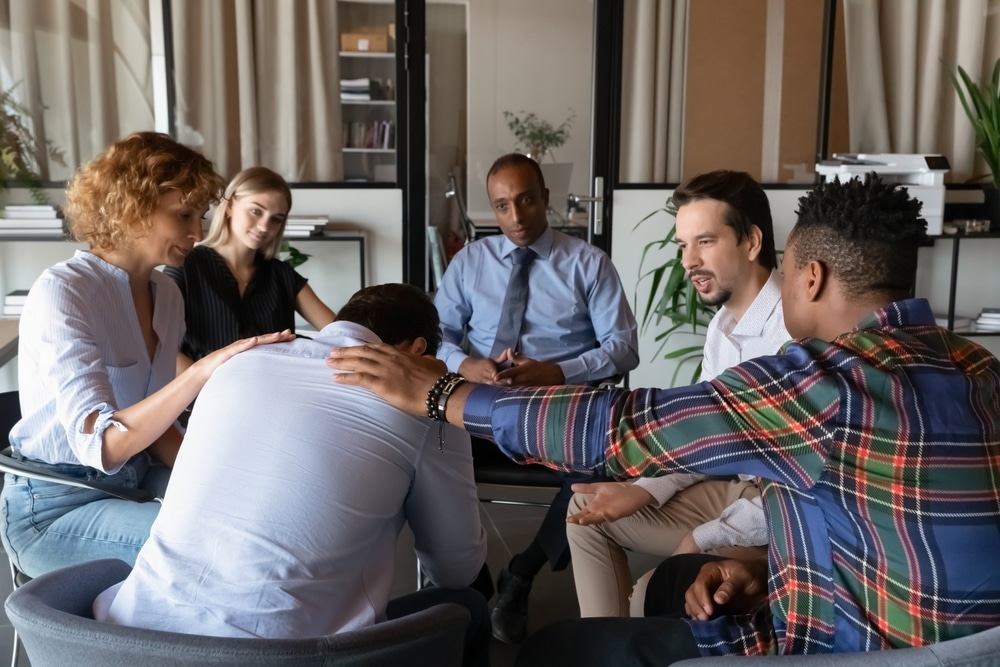 Depressed man thinking about addiction and substance abuse challenges during group rehabilitation counseling session