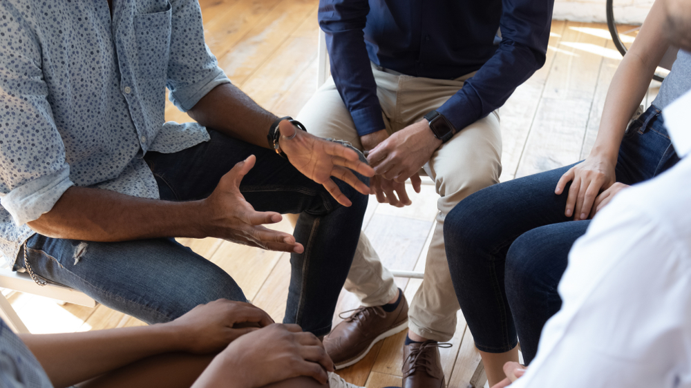 Substance abuse coping mechanisms and holistic approaches discussed by an African man counselor at a group therapy session in rehab